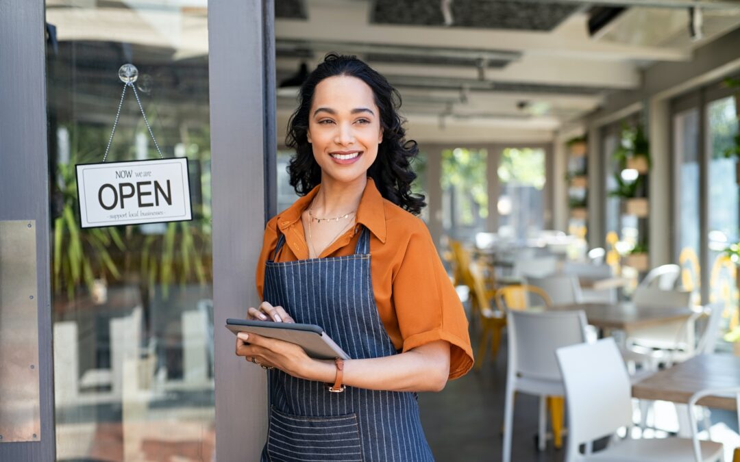 Small business entrepreneur at cafe entrance using digital tablet